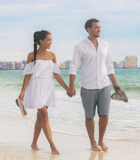 Man and woman walking on beach | best fabrics for summer holidays | The Sharp Gentleman
